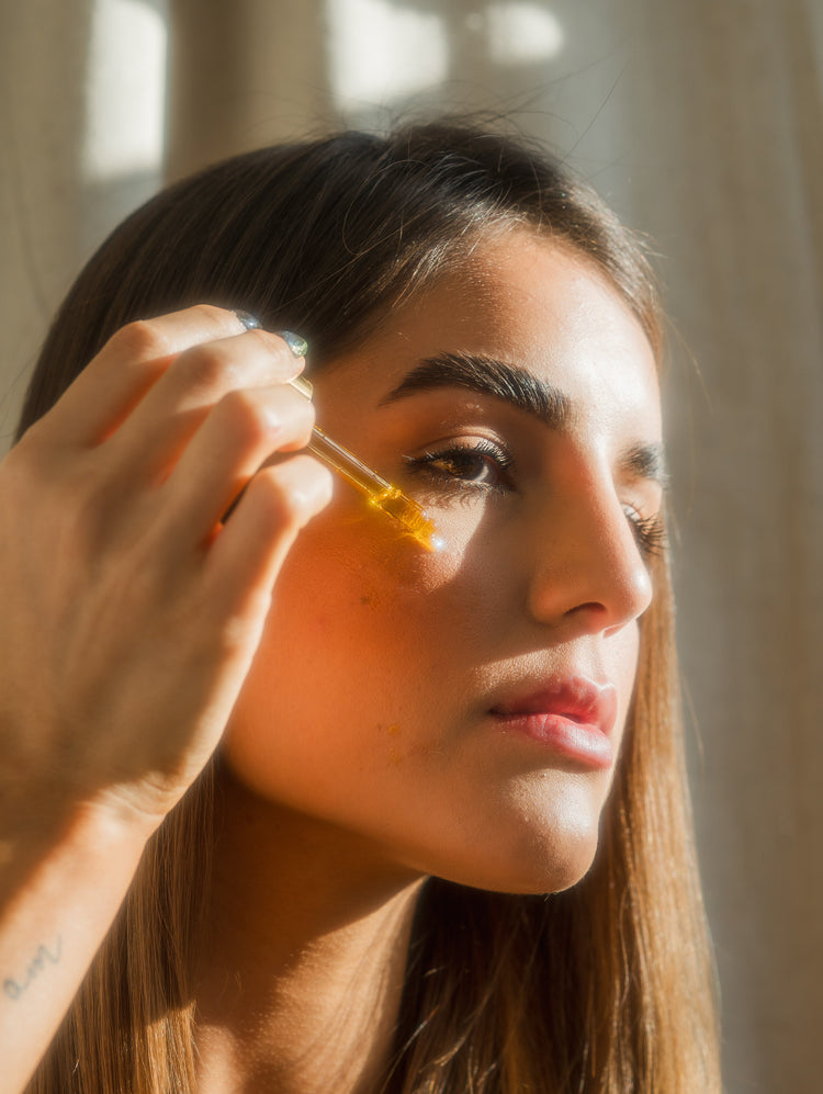 A female model applying a golden serum liquid over her chick